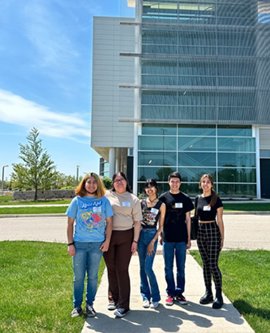 A group of Kalamazoo College students smiling and posing for a photo in front of the Stryker building.