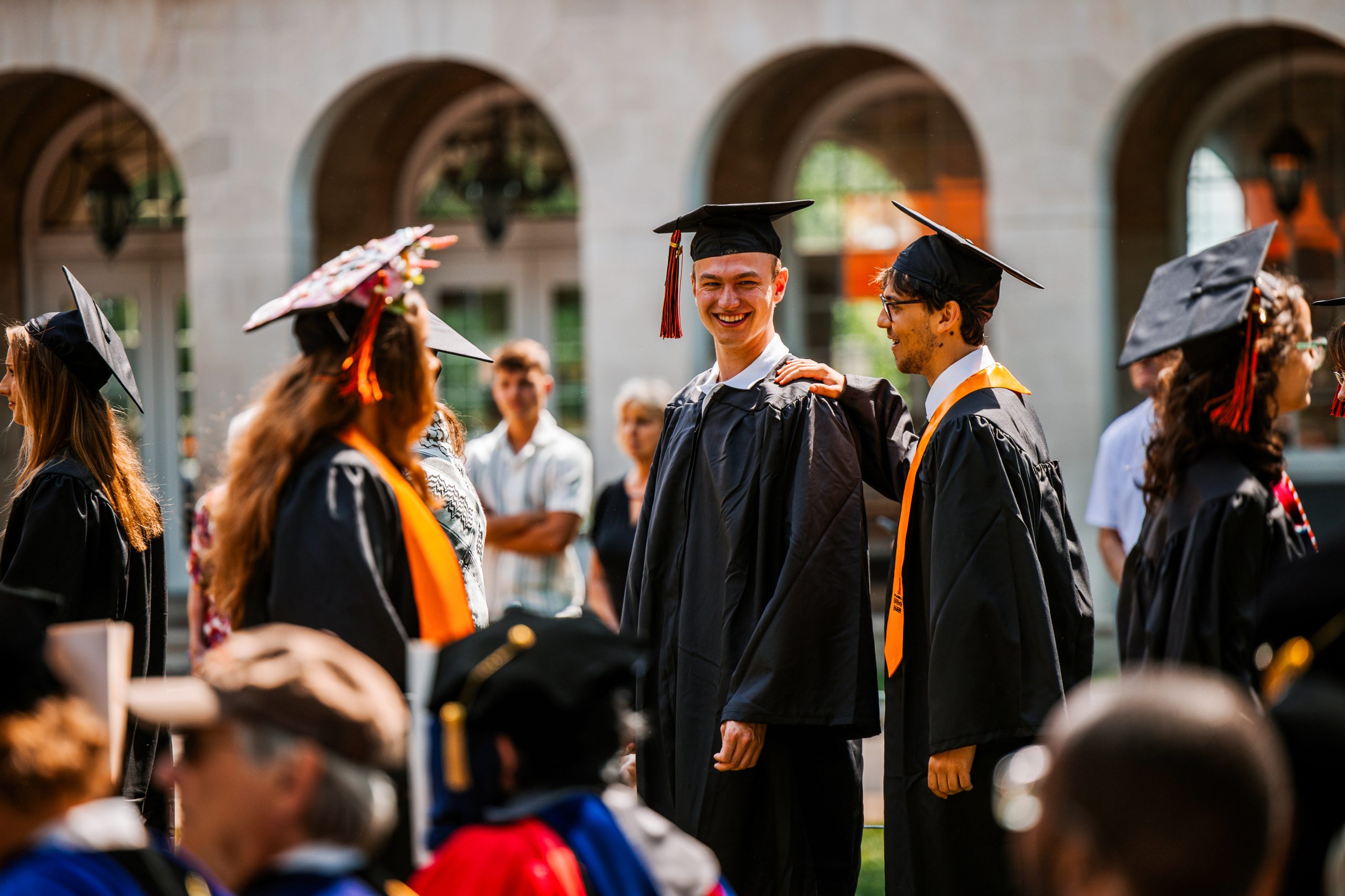 Group of smiling Kalamazoo College graduates in caps and gowns, standing together