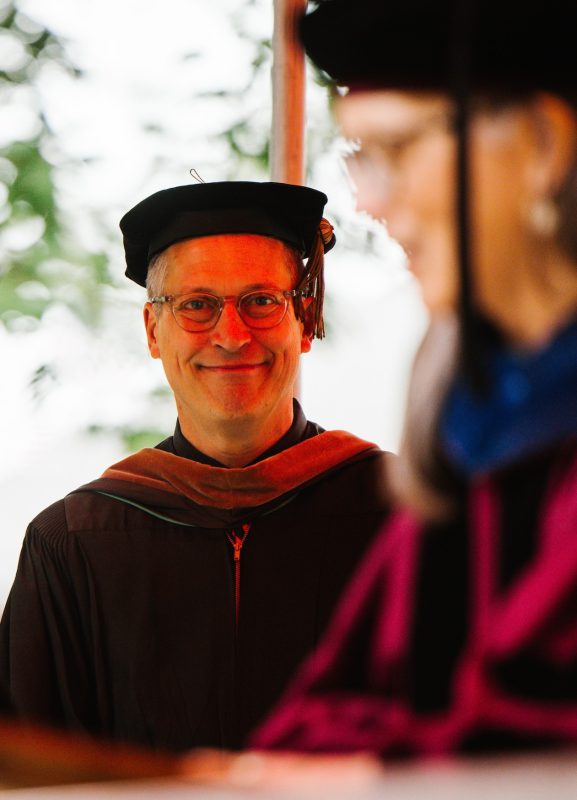 Community Medal of Arts Award recipient Lanny Potts smiling at a graduate during Commencement